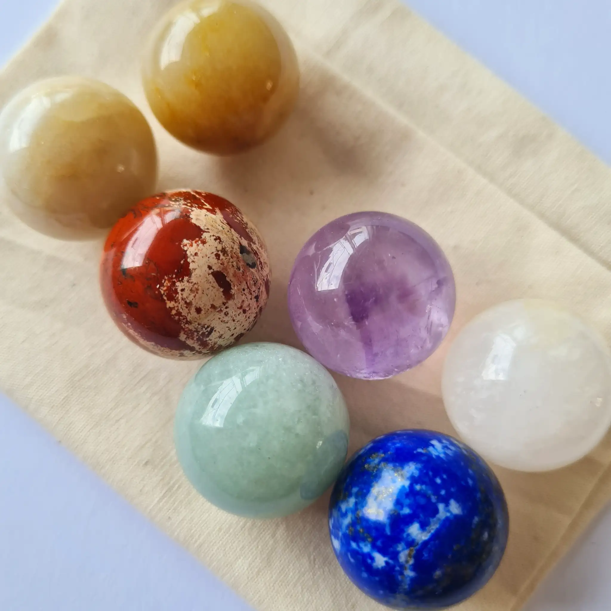 7 pierres des chakras posées sur un pochon en coton beige, pour rituel de purification et d’harmonisation énergétique
