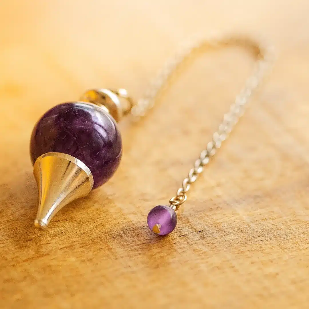 Pendule Séphoroton en améthyste sur fond bois clair – intuition, sérénité et guidance spirituelle.